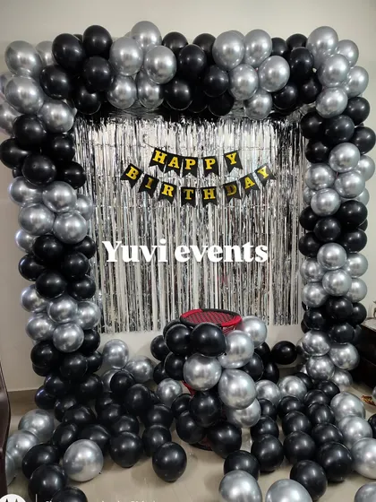 A simple and stylish black and silver balloon arch with a silver foil curtain. This is a great option for a modern birthday party at home.