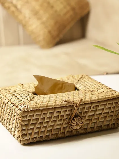 This rattan tissue box cover, with its neat weave and charming loop closure, is displayed on a side table. It seamlessly blends with the home decor, proving that even practical items can be beautiful.