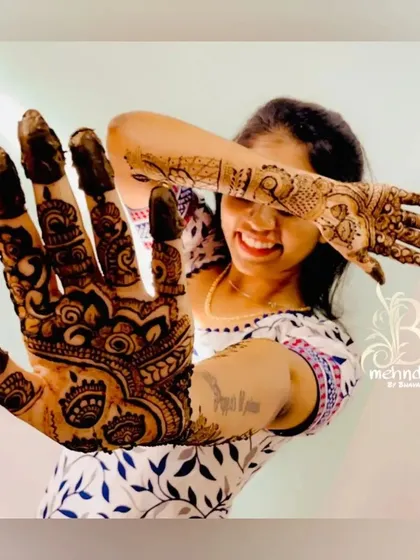 The joy of a fresh mehndi design. A happy client playfully shows off her intricate palm art.