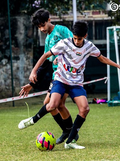 Two older players compete for the ball, showcasing the physical and technical aspects of the game at a higher level.