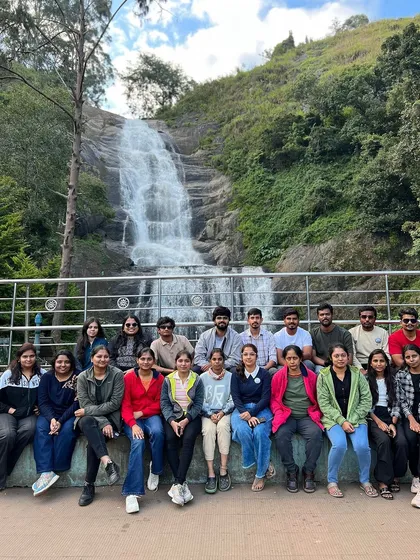 A group photo in front of a waterfall in Kodaikanal.