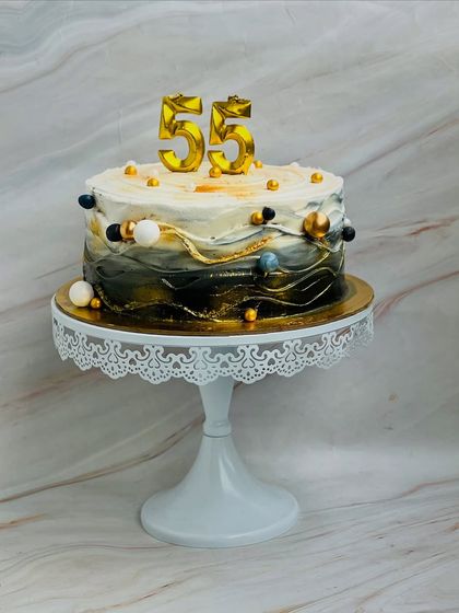 A modern and artistic cake for a 55th birthday celebration. The design features a beautiful wave effect in black, white, and gold, creating a sophisticated centerpiece for the party.
