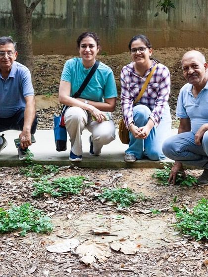 Participants of a "Joy Walk" at Aravali Creek pose near a patch of newly planted ground cover, feeling enchanted and relaxed in the urban forest.