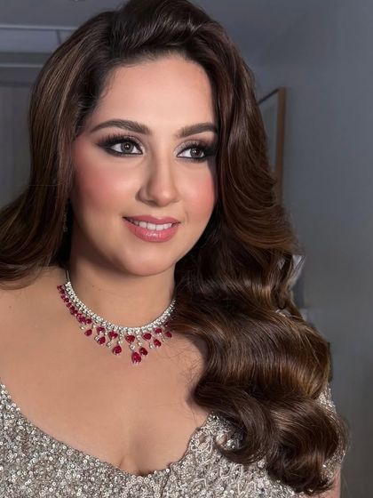 The bride smiling, her side-swept waves and smoky eye makeup creating a stunning combination.