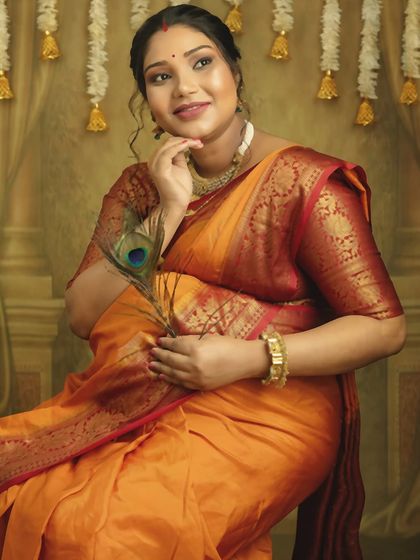 A thoughtful and elegant pose. This close-up in a beautiful silk saree, with a peacock feather for a prop, highlights your grace and the joy of this special time.