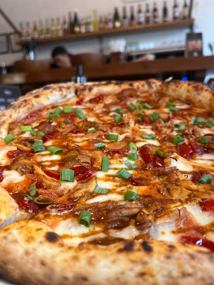 The Adobo Chicken pizza sitting pretty on the counter, with the cozy ambiance of our pizzeria in the background.