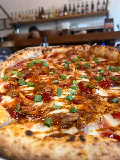 The Adobo Chicken pizza sitting pretty on the counter, with the cozy ambiance of our pizzeria in the background.