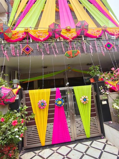 A complete wedding home look, from the full-building drapes to the decorated gate and blooming flowers, creating a picture-perfect scene.