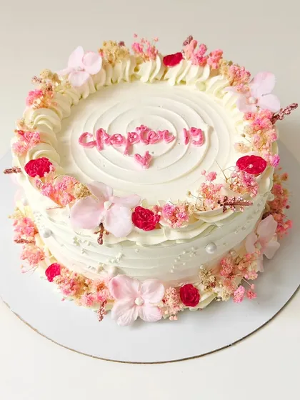 "Chapter 19." A beautiful vintage-style cake decorated with a wreath of dried baby's breath and other delicate flowers. The soft, rustic look is perfect for a special birthday.