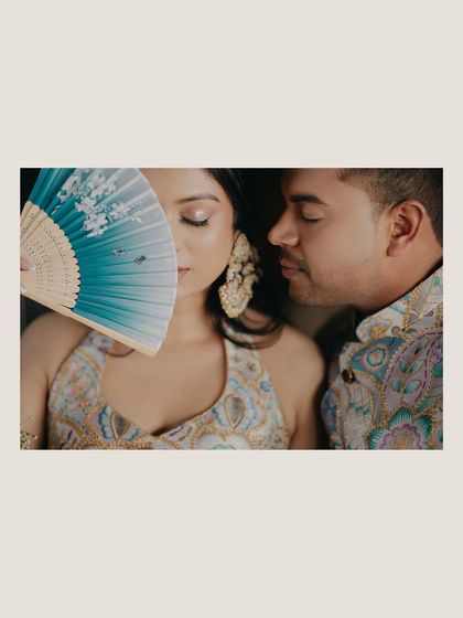 An artistic close-up from the Haldi ceremony. The fan partially obscuring the bride's face adds a touch of mystery and elegance to this intimate portrait.