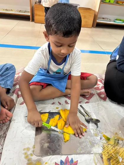 Practical life skills are at the core of my program. Here, a young child practices concentration and fine motor control by carefully cutting a mango, learning independence and contributing to a real-life task.