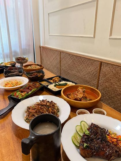 A New Year's feast spread across the table. This is how we celebrate, with an abundance of dishes like pork ribs, noodles, curries, and rice, meant to be shared with family and friends.
