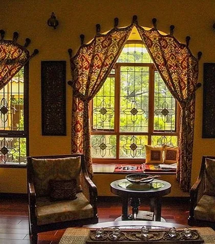 For the residence of Roopa Hariprasad, we focused on creating richly detailed interiors that reflect traditional Indian artistry. This seating area features custom-designed window treatments and intricate grillwork, creating a warm and evocative space for relaxation.
