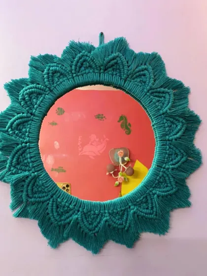 A beautiful sunburst-style macrame mirror in a rich teal color. This design adds a pop of color and a touch of bohemian elegance, perfect for an entryway or bedroom.