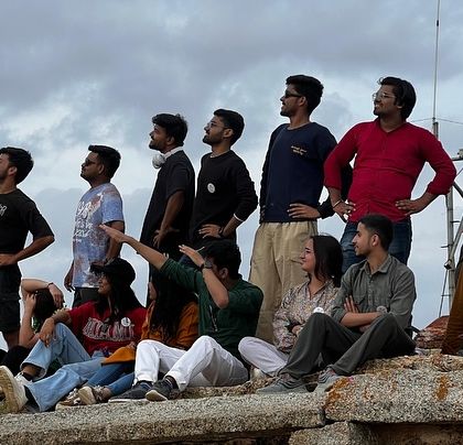 A group of friends enjoying the view from a hilltop, looking towards the horizon.