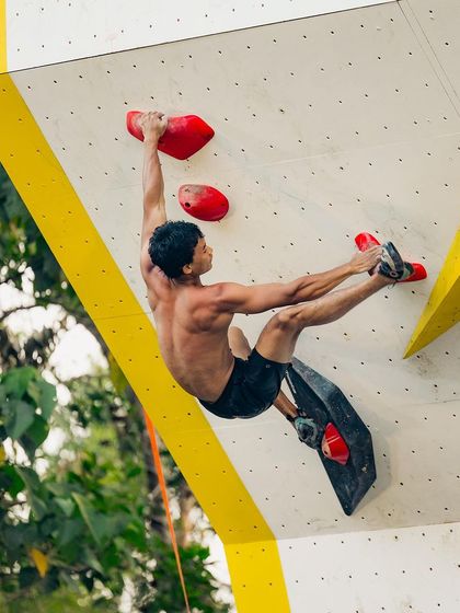 This dynamic move, known as a 'dyno', shows the athleticism required in psicobloc climbing. The climber is airborne, reaching for the next hold.