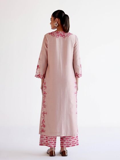 The back view of the light pink kurta, showing the continuous line of floral embroidery that runs down the sides.