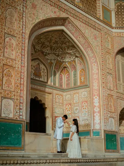 A gesture of old-world romance in front of the intricately painted walls of Amber Fort. This is the kind of timeless, royal pre-wedding photograph that becomes a cherished family heirloom.