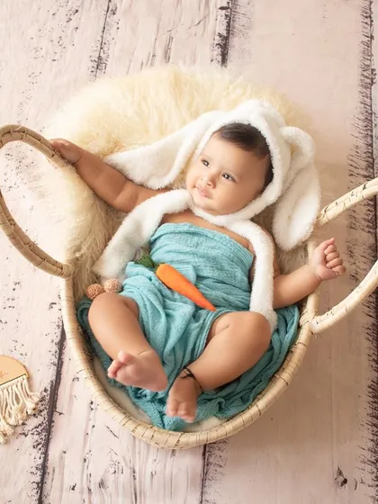 Some bunny is six months old. This adorable baby is dressed as a bunny with a carrot prop for a playful half-birthday shoot.