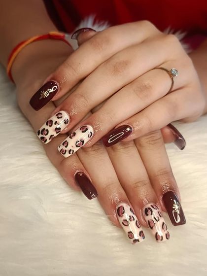 A bold and fun set featuring a mix of deep maroon polish and classic leopard print on long, square-shaped extensions.