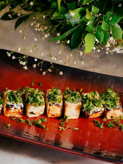The Paneer Ajamod Tikka, beautifully plated on a rustic dish. The vibrant green topping contrasts wonderfully with the grilled paneer.