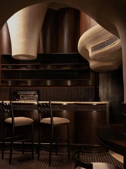 A detail of the bar, showing the fluted woodwork and the organic, overhanging ceiling structures. Every texture is chosen to contribute to a cohesive, sensory-driven environment.