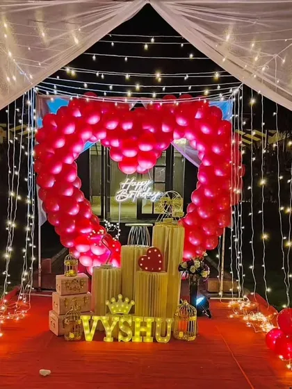 We specialize in creating unforgettable romantic surprises. This stunning outdoor cabana setup features a heart-shaped balloon arch, a red carpet entrance, and magical fairy lights, perfect for a birthday or anniversary celebration.