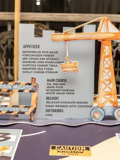 A custom-designed menu holder in the shape of a crane adds a playful yet functional detail to the construction party table.
