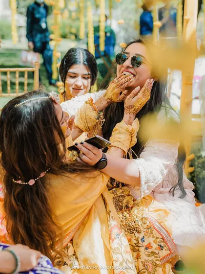 A candid moment of mischief and laughter as the bride's friends playfully apply Haldi to her face.
