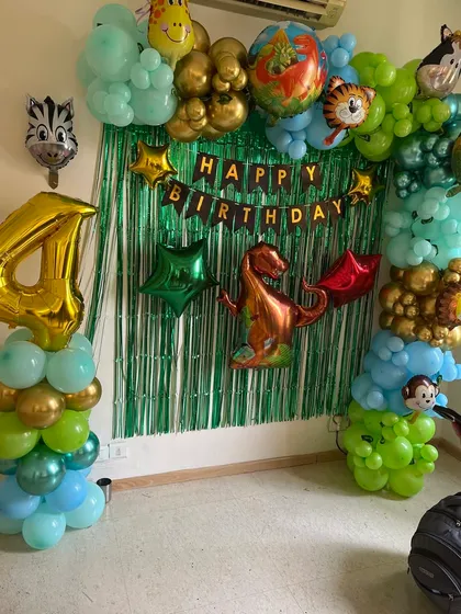 A compact Dinosaur and jungle animal theme decoration, perfect for a small space at home, featuring a green fringe backdrop and animal foil balloons.