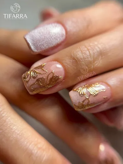 A beautiful combination of textures, with hand-drawn gold florals on a nude base next to a nail with a shimmering pink cat-eye effect.