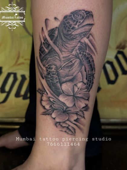 A stunningly realistic sea turtle tattoo on the leg, surrounded by hibiscus flowers. This piece combines our love for marine life and floral art, with detailed shading that makes the turtle appear three-dimensional.