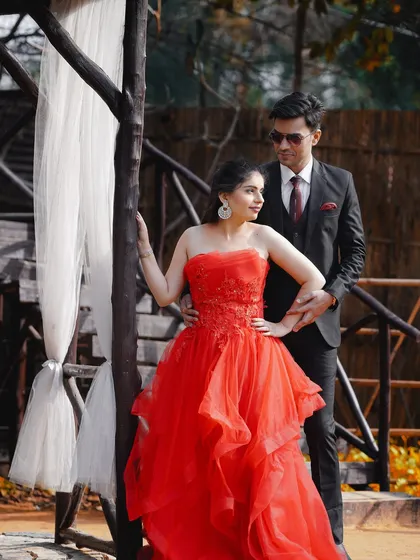 A dramatic and romantic pose from a pre-wedding shoot. The bride's flowing red gown and the couple's intense gaze make for a truly cinematic shot.