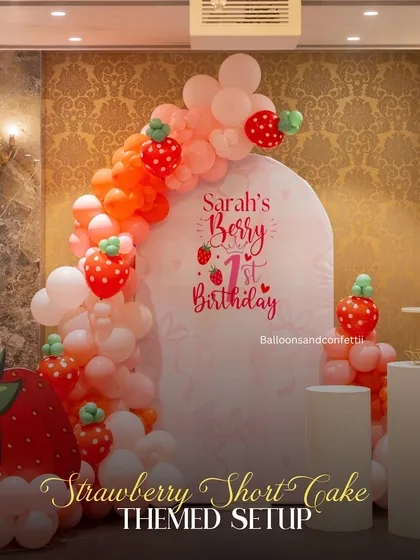 A 'berry' sweet 1st birthday. This Strawberry Shortcake theme features a custom arched backdrop and a pink and red balloon garland with cute strawberry details.