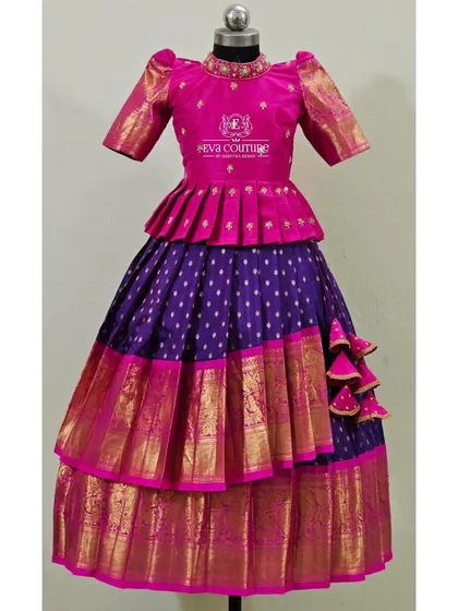 A tiered Kanchi Pattu lehenga in pink and purple. The peplum blouse and layered skirt create a very grand and festive look.