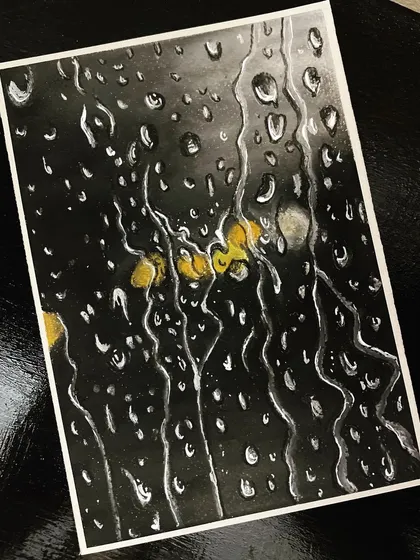 Inspired by the monsoon season, I created this piece showing raindrops on a window pane. I used oil pastels on black paper to capture the realistic look of water droplets and reflections.