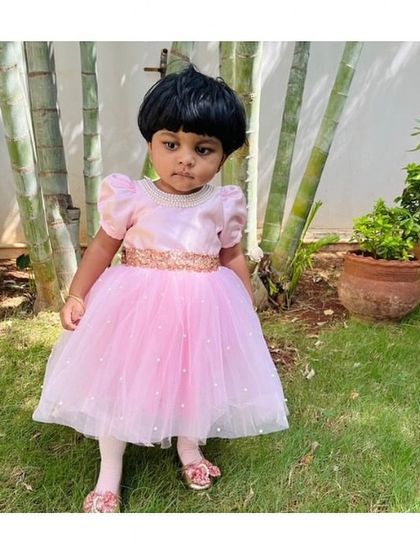 Pretty in pink and pearls. This little one is ready for her party in a classic pink tulle dress, accented with a sparkling sequin belt for a touch of glamour.