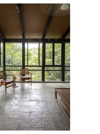 An upper-level room at the 'Villa in a Grove', with large windows framing the dense canopy outside. It feels like a treehouse, a private retreat nestled in nature.