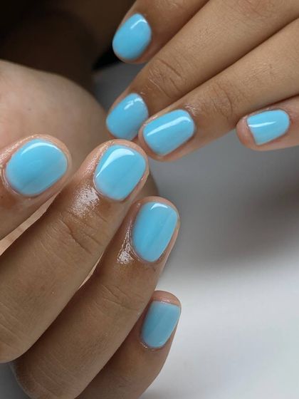 A bright, pastel blue manicure on short, rounded nails. This fun and fresh color is perfect for a playful and modern look.