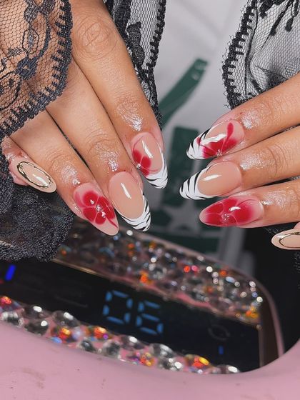 A bold and artistic design with translucent red floral painting over a striking black and white zebra-print French tip.