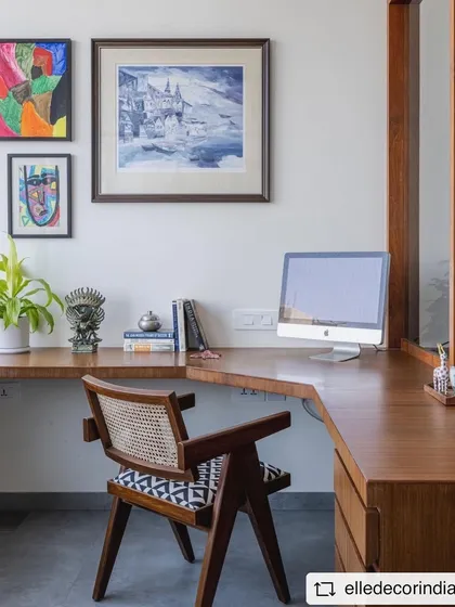 The study area in the 'Sepalika' office, featuring a custom wooden desk, a classic cane-backed chair, and a gallery wall of personal art.