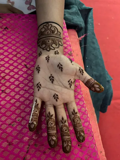 Elegance in simplicity. This is a perfect example of a guest mehendi design, featuring delicate leaf motifs on the palm and intricate bands on the fingers, applied quickly without compromising on beauty.