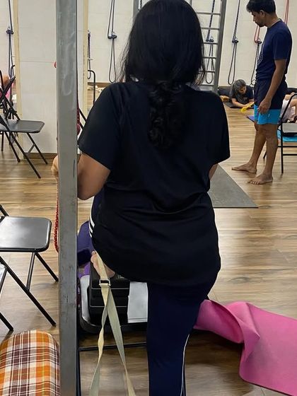 A student using a stall bar for support. The studio is equipped with various props to assist in a wide range of asanas.