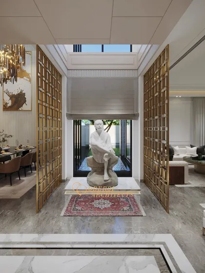 A central courtyard space featuring a serene sculpture, framed by golden jaali screens that separate it from the living and dining areas.
