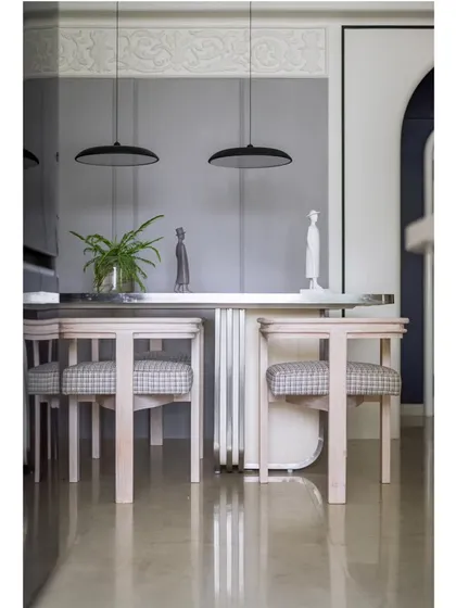 A reflection of the dining area, highlighting the intricate details of the wall moulding and the elegant suspended lights.