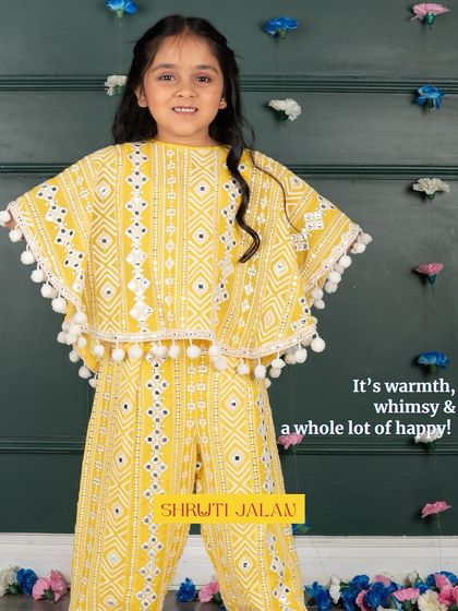 It's warmth, whimsy, and a whole lot of happy. This little girl is wearing my yellow pom-pom cape set, a cheerful and playful outfit that’s perfect for any celebration.