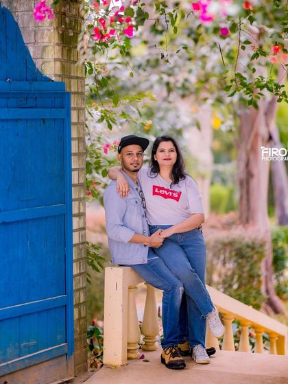 A casual and relaxed couple's portrait on a bridge with a blue gate.