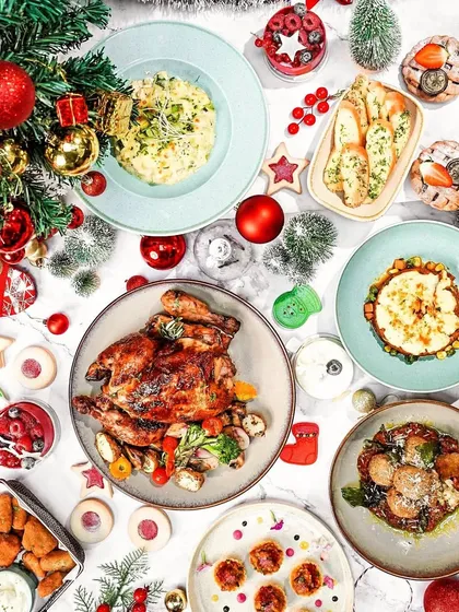 A festive Christmas brunch flatlay on a white marble surface. The top-down view captures the entire celebratory spread in a clean and organized composition.