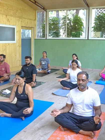 Find your focus in our sunlit shala. Participants in a morning yoga class, breathing together and finding their center in our peaceful studio environment.