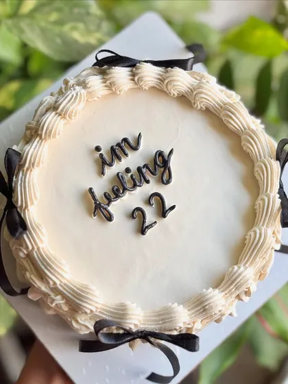 "I'm feeling 22." This vintage-style cake with black ribbons and classic piping is perfect for celebrating with a touch of Taylor Swift-inspired sass.